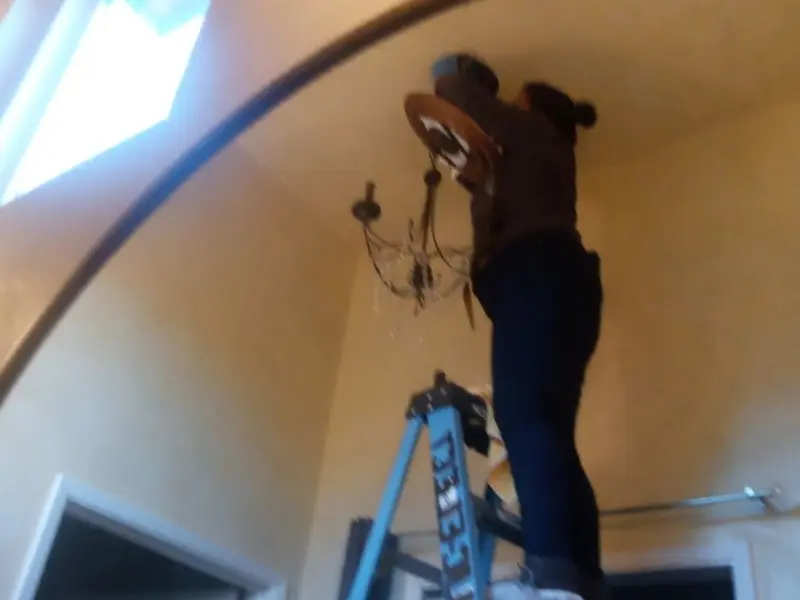 Electrician installing a chandelier in a Corona de Tucson residence